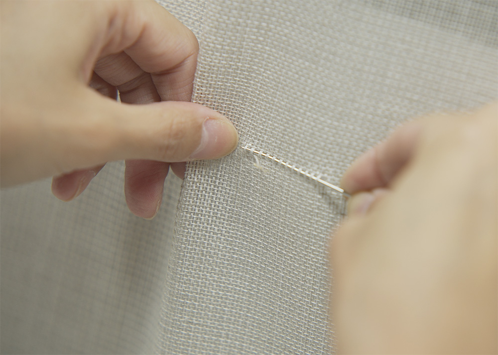 織り目を揃えるための工程。手加工品ならではの繊細なひと手間が、壁紙の仕上りを左右する。