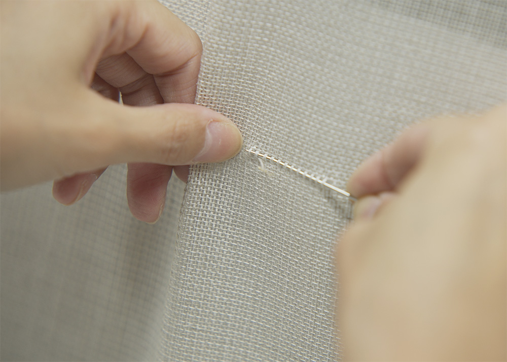 織り目を揃えるための工程。手加工品ならではの繊細なひと手間が、壁紙の仕上りを左右する。